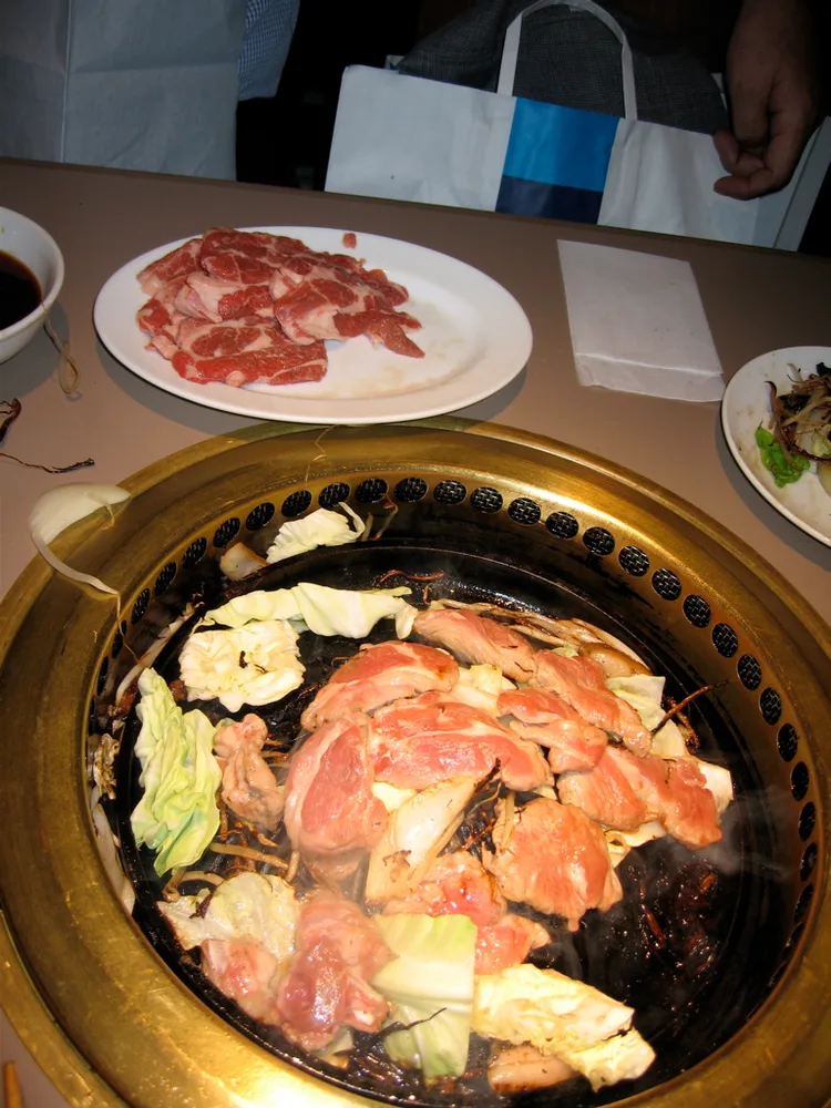 구워 먹는 징기스칸. 양고기를 직접 구워 먹는 식사라 빠른 한 끼보다 저녁에 시간을 넉넉히 잡기 좋습니다. 조리 형태 예시이며 다루마의 특정 메뉴나 좌석 사진이 아닙니다.